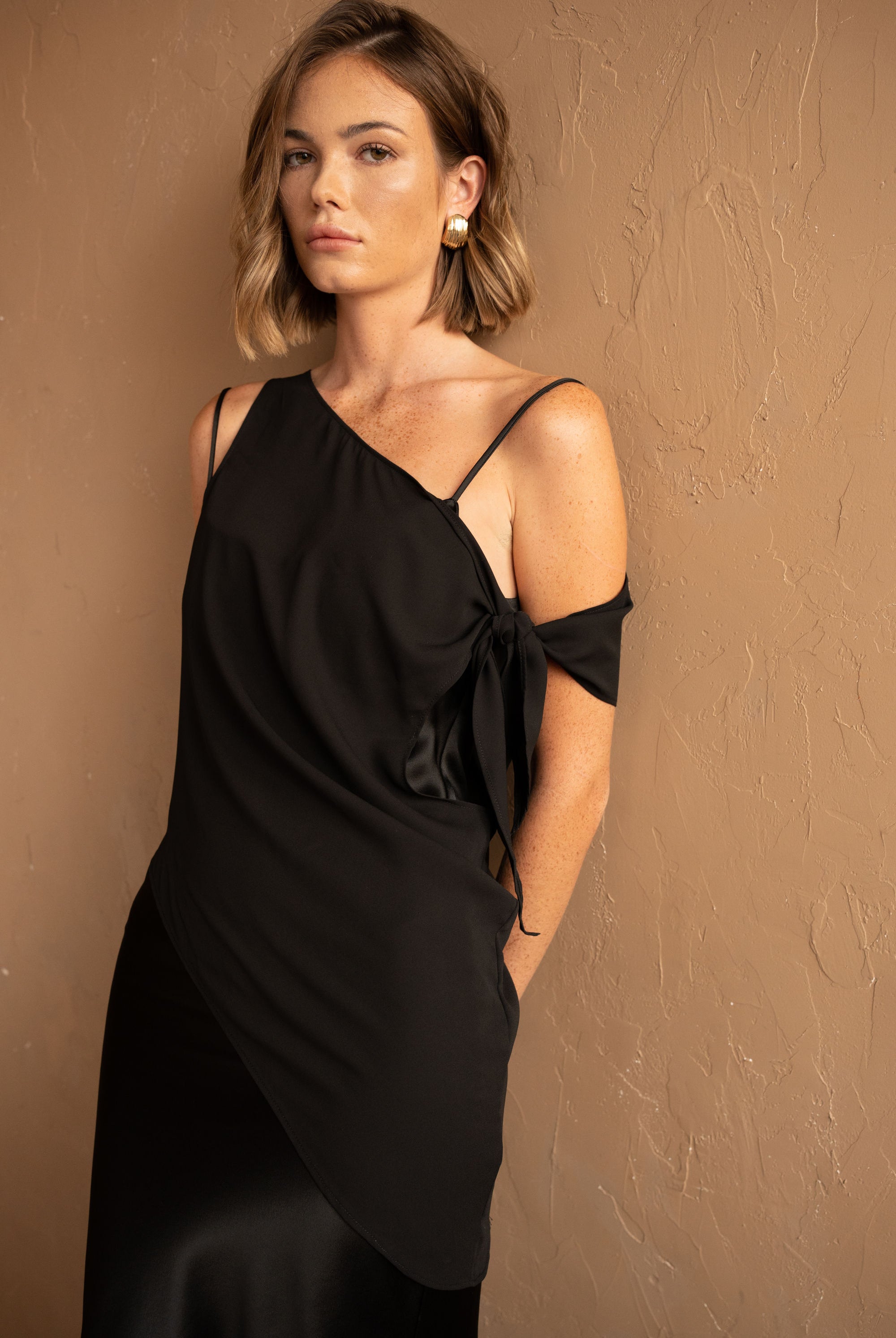 Front view with brown background of Asymmetrical Mesh-Spliced Satin Maxi Dress – Black by Aisl.